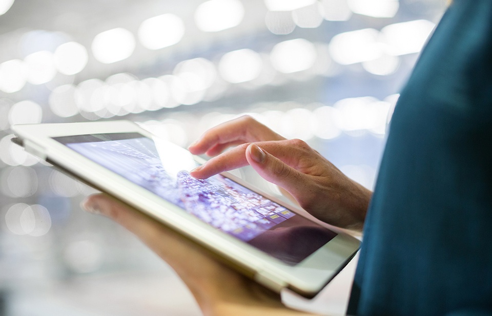 person hands holding a tablet with economic information on screen