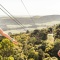 Two people on a zipline over treetops with EcoZip Adventures